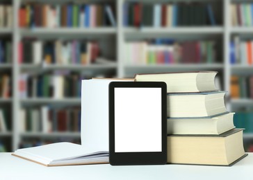Image of Hardcover books and modern e-book on white table in library