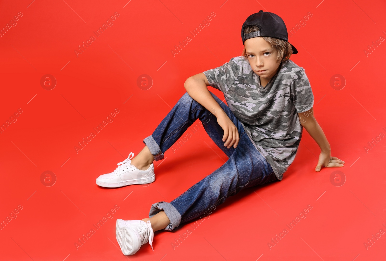 Photo of Cute little boy in casual outfit on red background