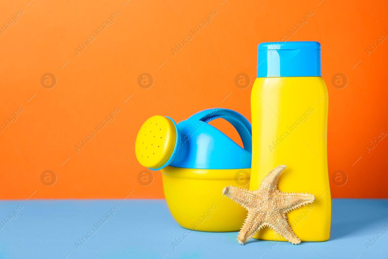 Photo of Different suntan product and plastic beach toy on color background. Space for text