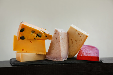 Photo of Different types of delicious cheeses on slate plate, closeup