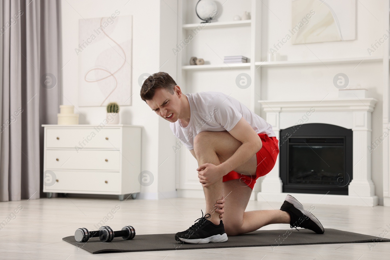 Photo of Man suffering from leg pain on mat at home