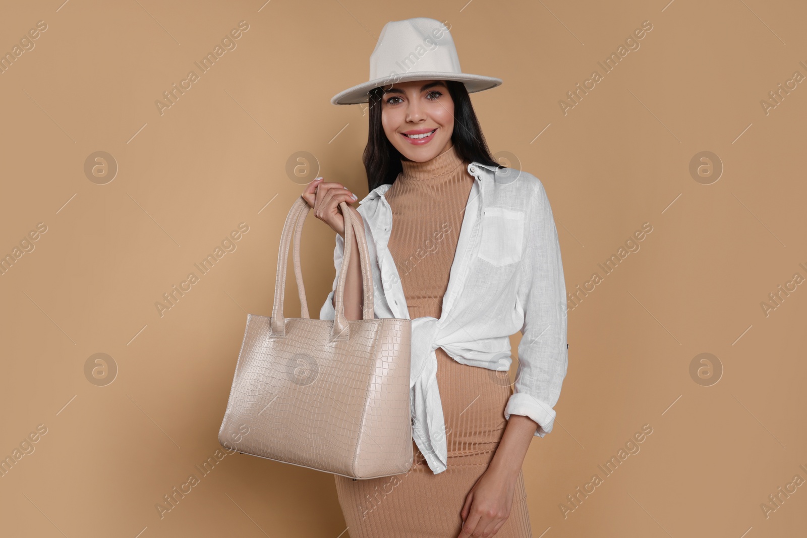 Photo of Young woman with stylish bag on beige background