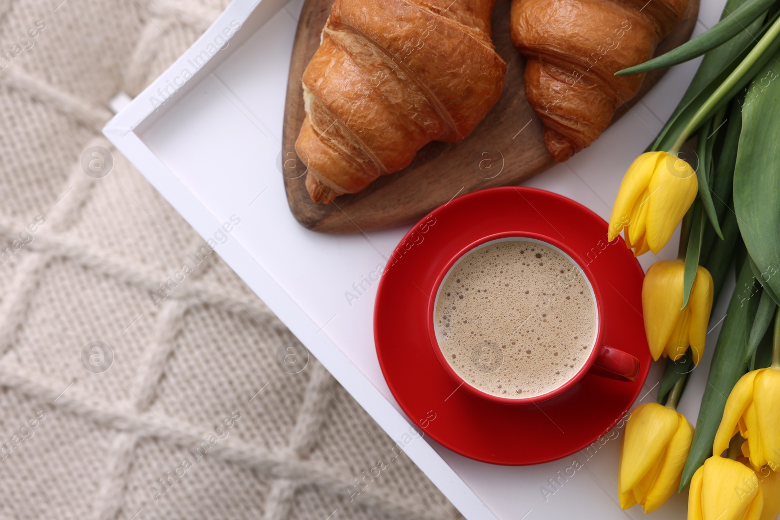 Photo of Morning coffee, croissants and flowers on knitted plaid, top view. Space for text