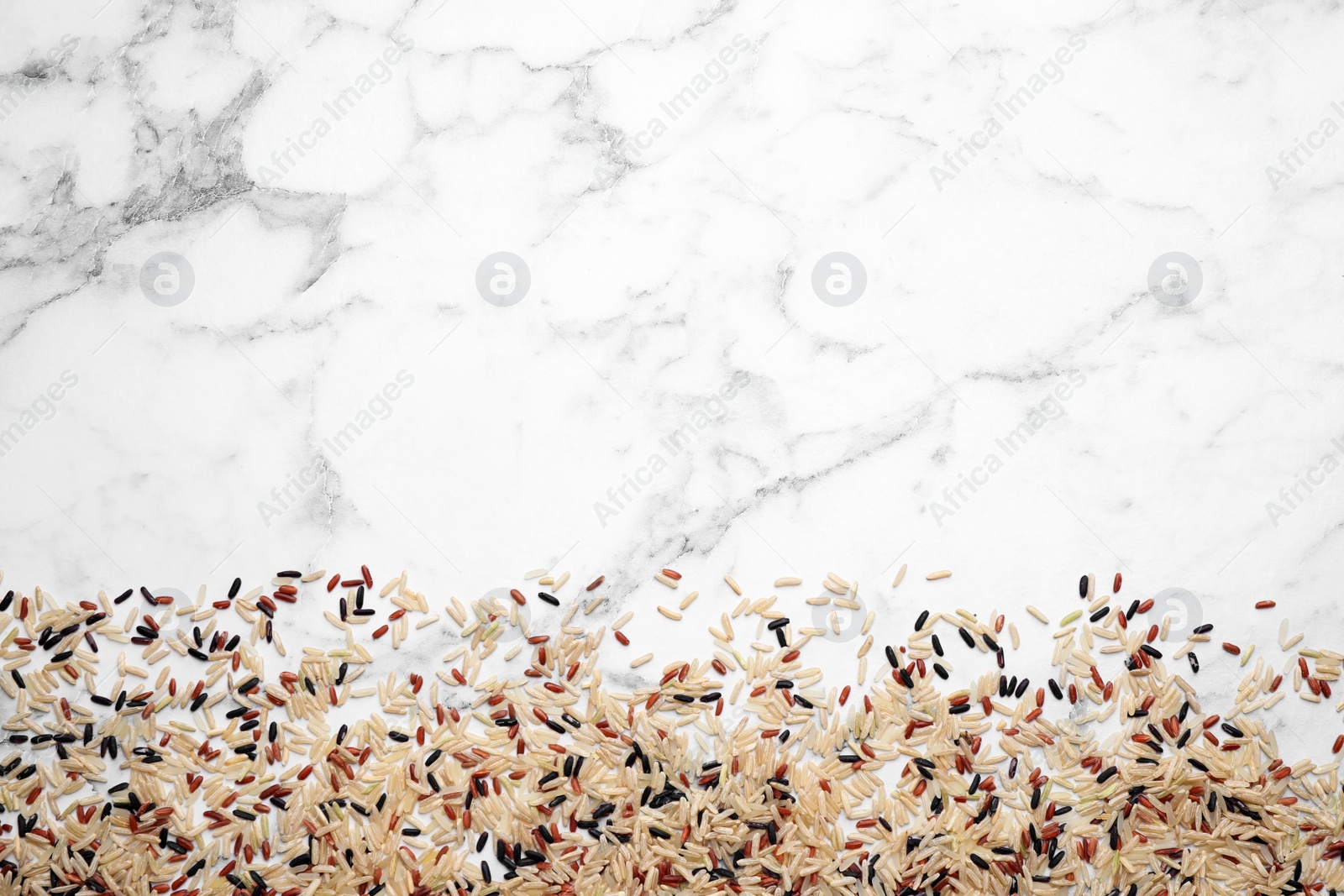 Photo of Mix of brown rice on marble table, top view. Space for text