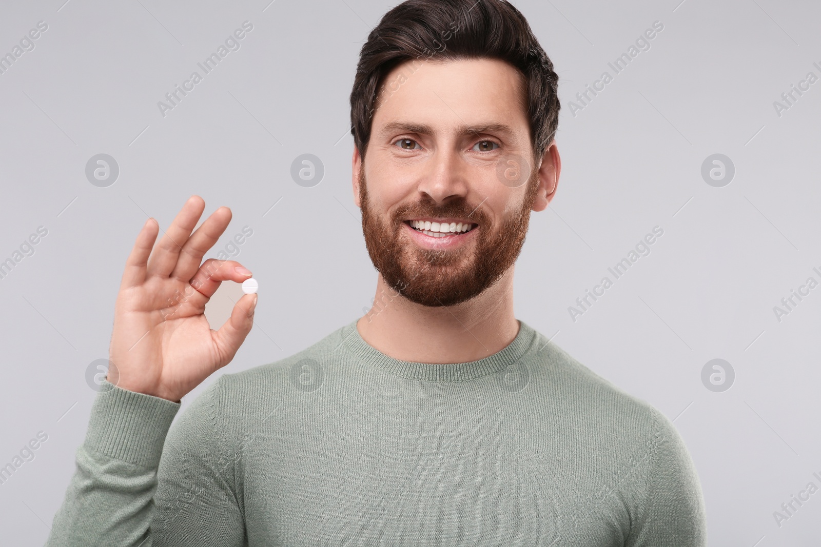 Photo of Handsome man with pill on light grey background