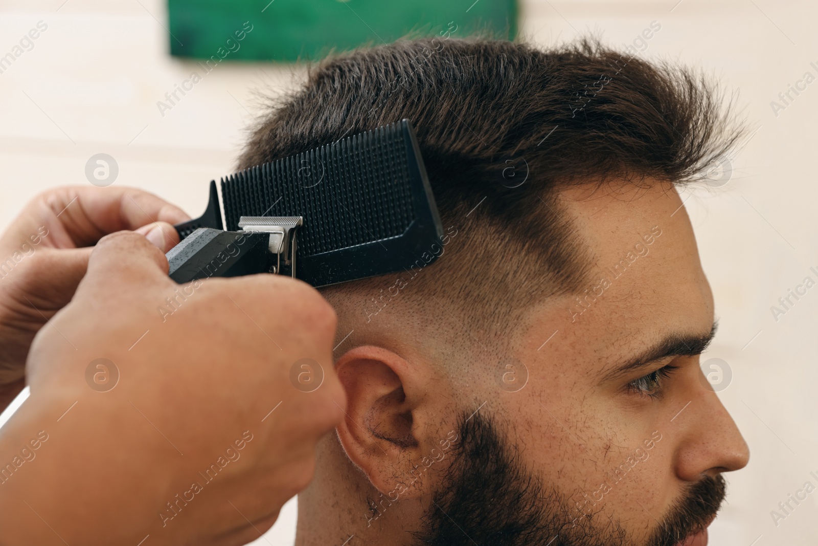 Photo of Professional hairdresser working with client in barbershop, closeup