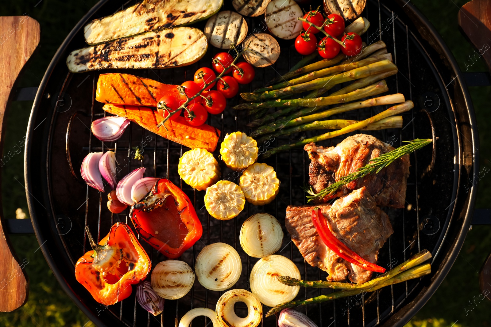 Photo of Delicious grilled vegetables and meat on barbecue grill outdoors, top view