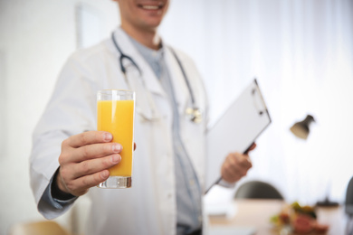 Nutritionist with glass of juice in office, closeup