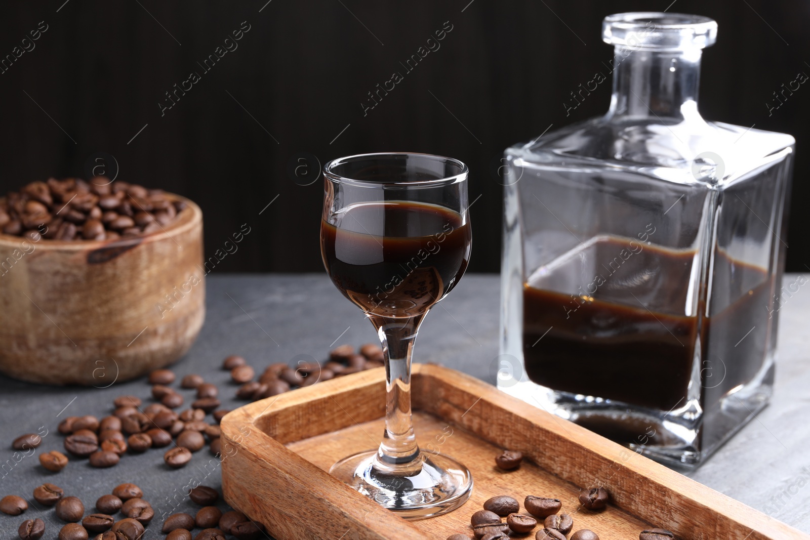 Photo of Coffee liqueur and beans on grey table