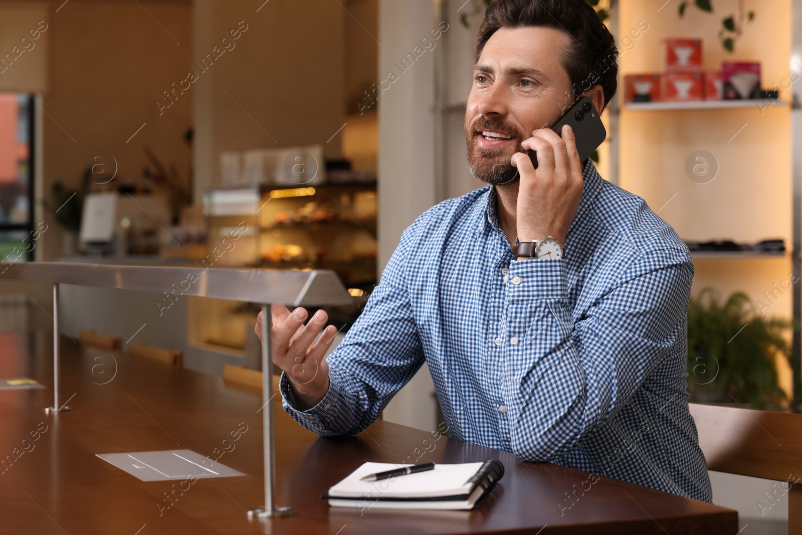 Photo of Handsome man talking on phone at table in cafe