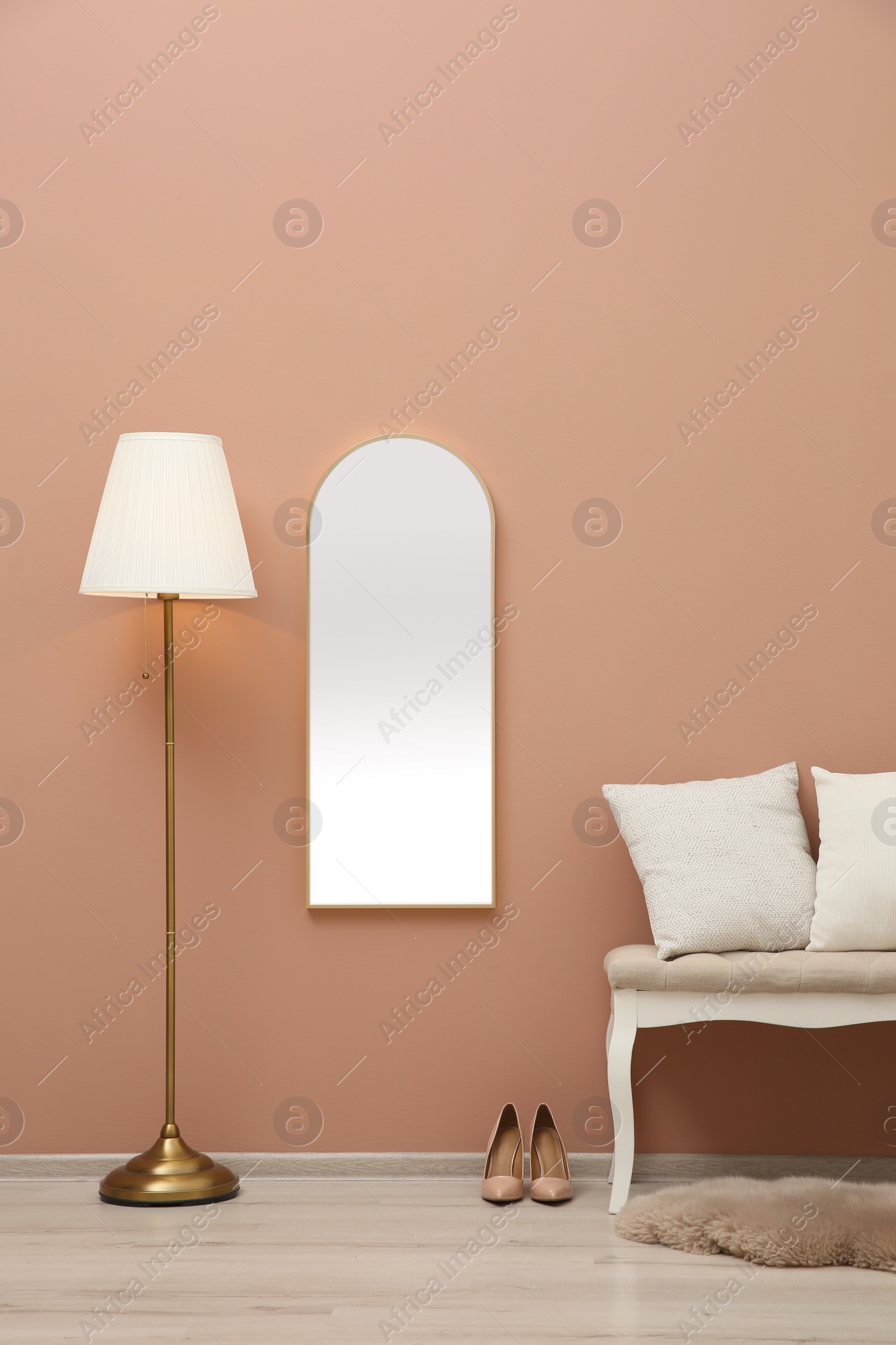 Photo of Room interior with white bench and mirror hanging on light pink wall. Stylish accessories