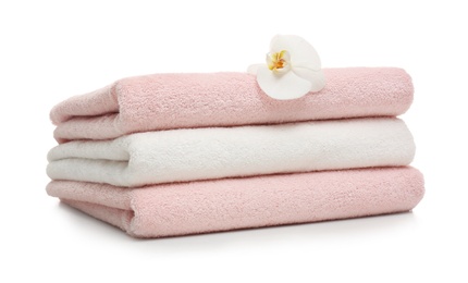 Stack of clean folded towels with flower on white background