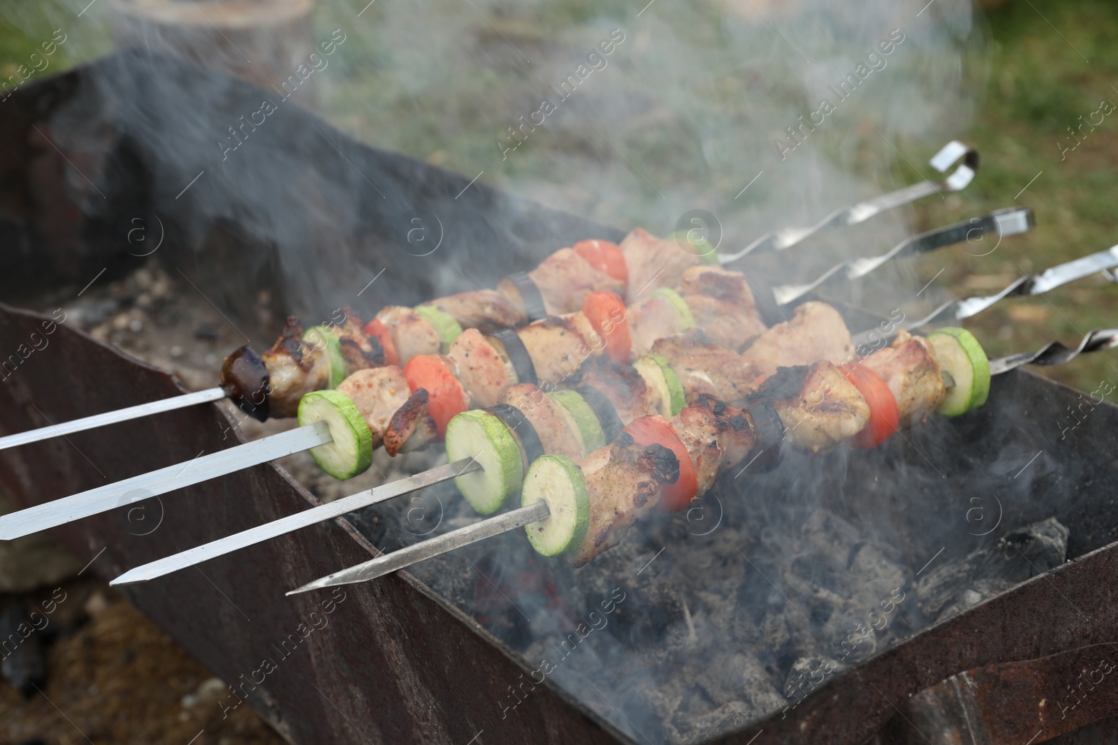 Photo of Cooking meat and vegetables on brazier outdoors