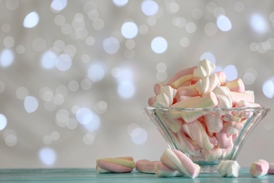 Photo of Delicious marshmallows in bowl on table against blurred background, closeup. Space for text