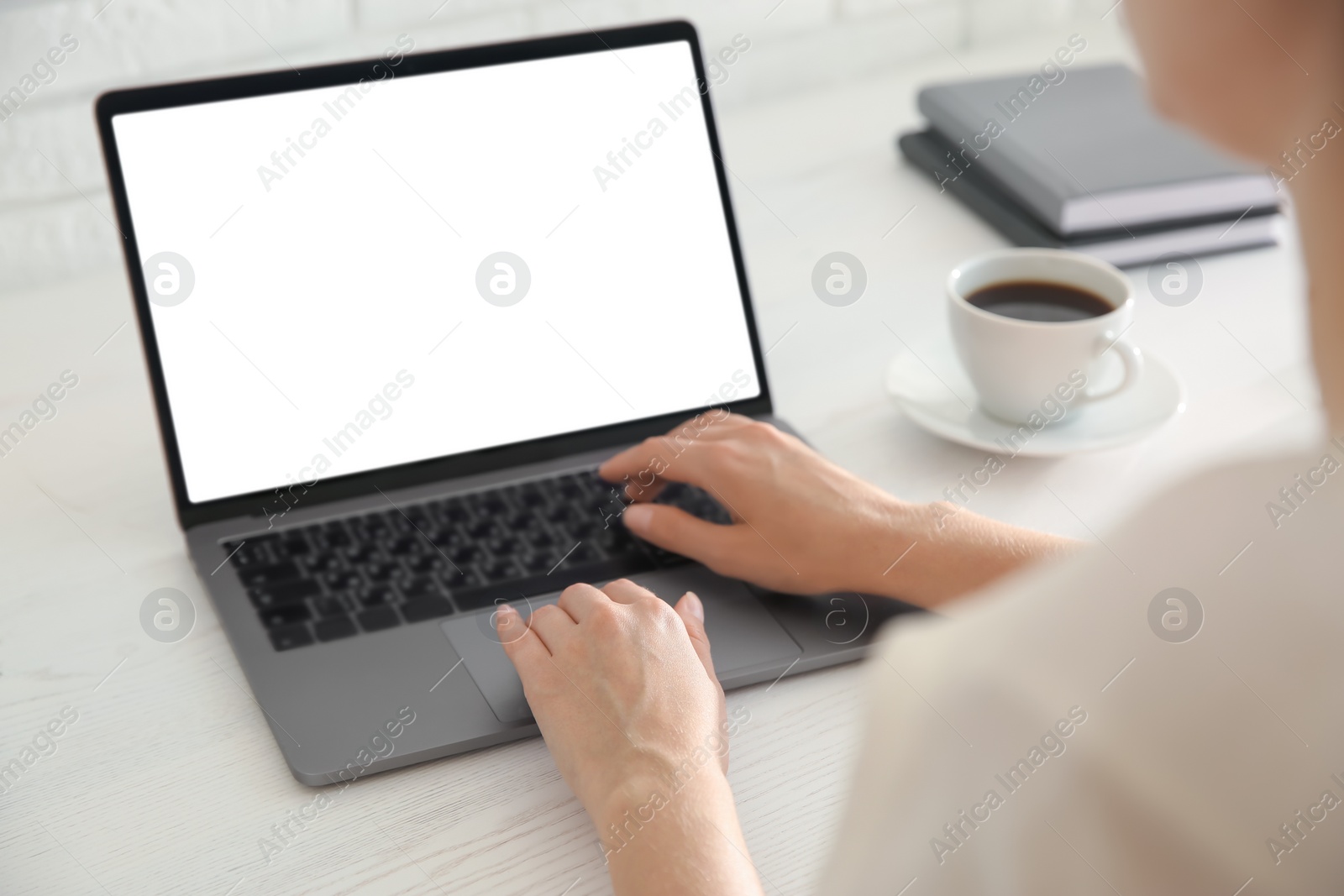 Photo of Woman working with modern laptop at white wooden table, closeup. Space for design