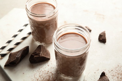 Photo of Jars with tasty chocolate milk on table. Dairy drink
