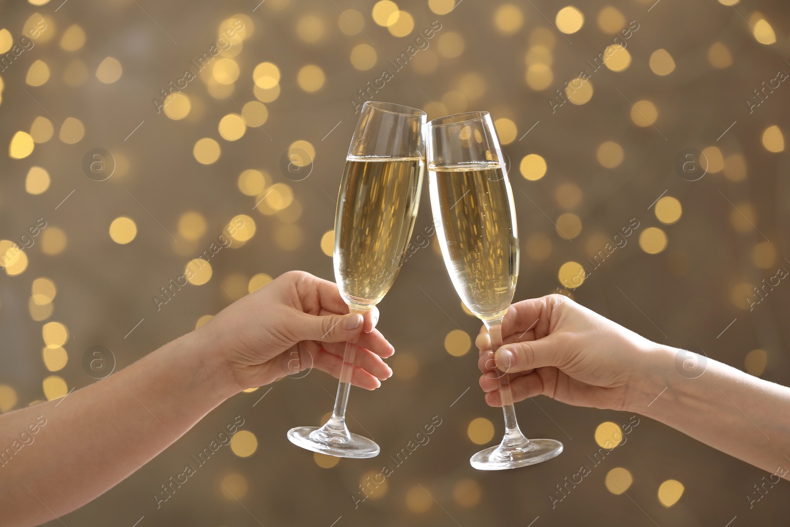 Photo of People clinking glasses of champagne on blurred background, closeup