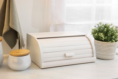 Wooden bread box and decorative elements on white countertop in kitchen