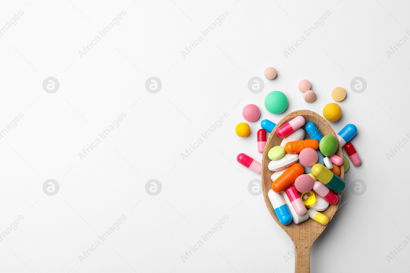 Photo of Spoon and pills on white background, top view