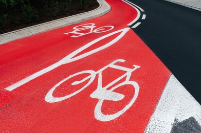 Red bike lane with painted white bicycle sign on city street