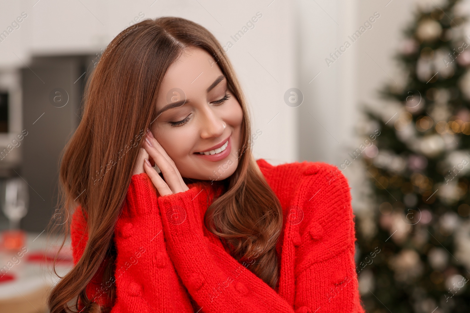 Photo of Beautiful young smiling woman near Christmas tree at home, space for text