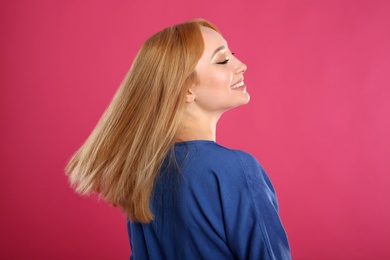 Photo of Beautiful young woman with blonde hair on pink background