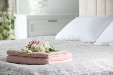 Photo of Terry towels with beautiful flowers on bed indoors, space for text