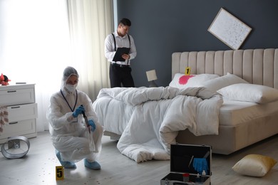 Photo of Investigators working at crime scene in messy room