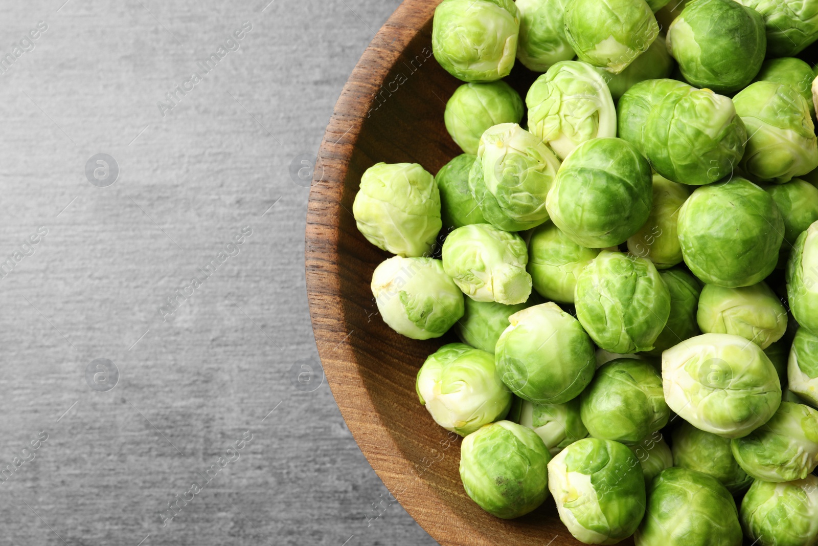 Photo of Bowl of fresh Brussels sprouts on grey background, top view with space for text