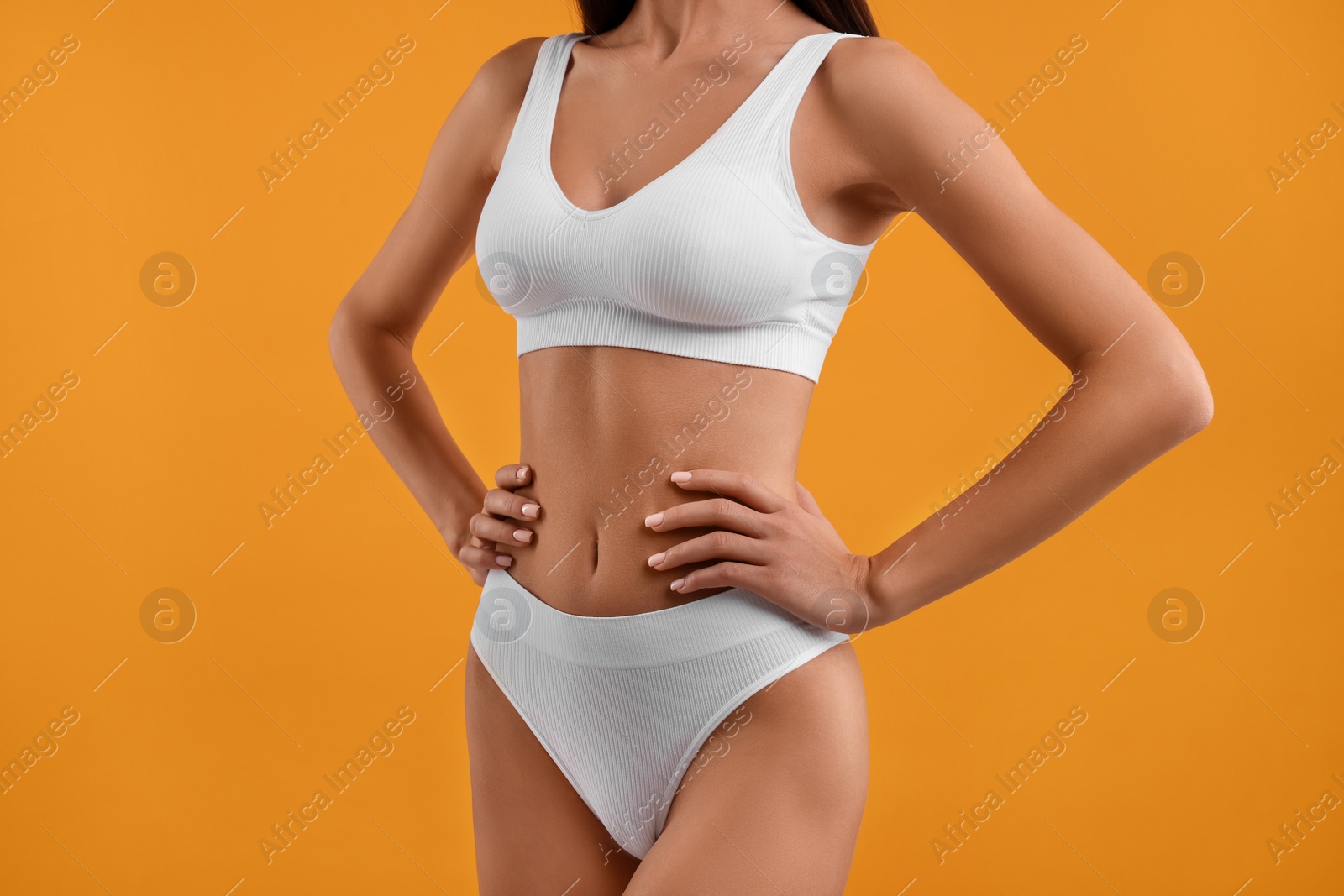 Photo of Young woman in stylish white bikini on orange background, closeup