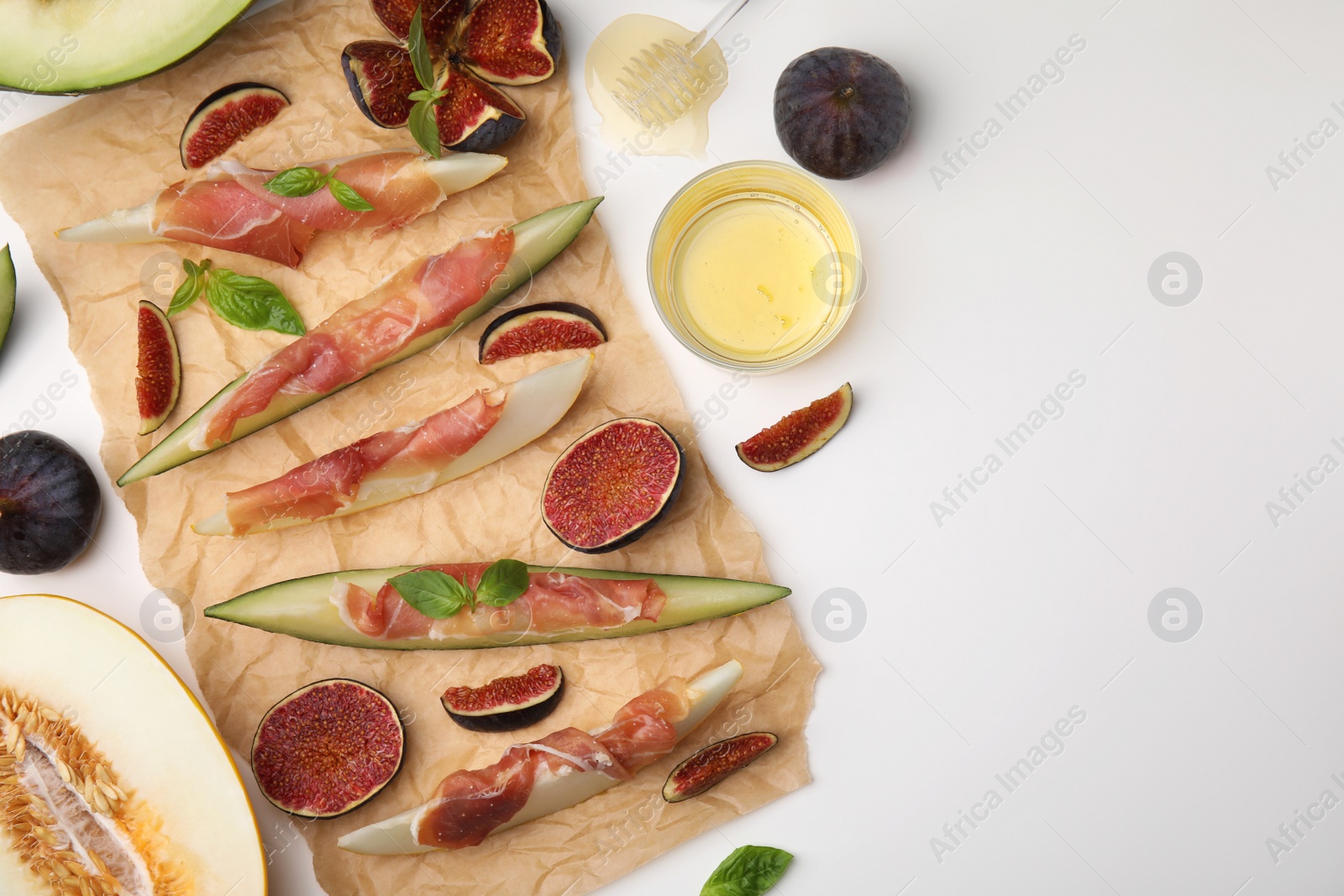 Photo of Tasty melon, jamon and figs served on white table, flat lay. Space for text