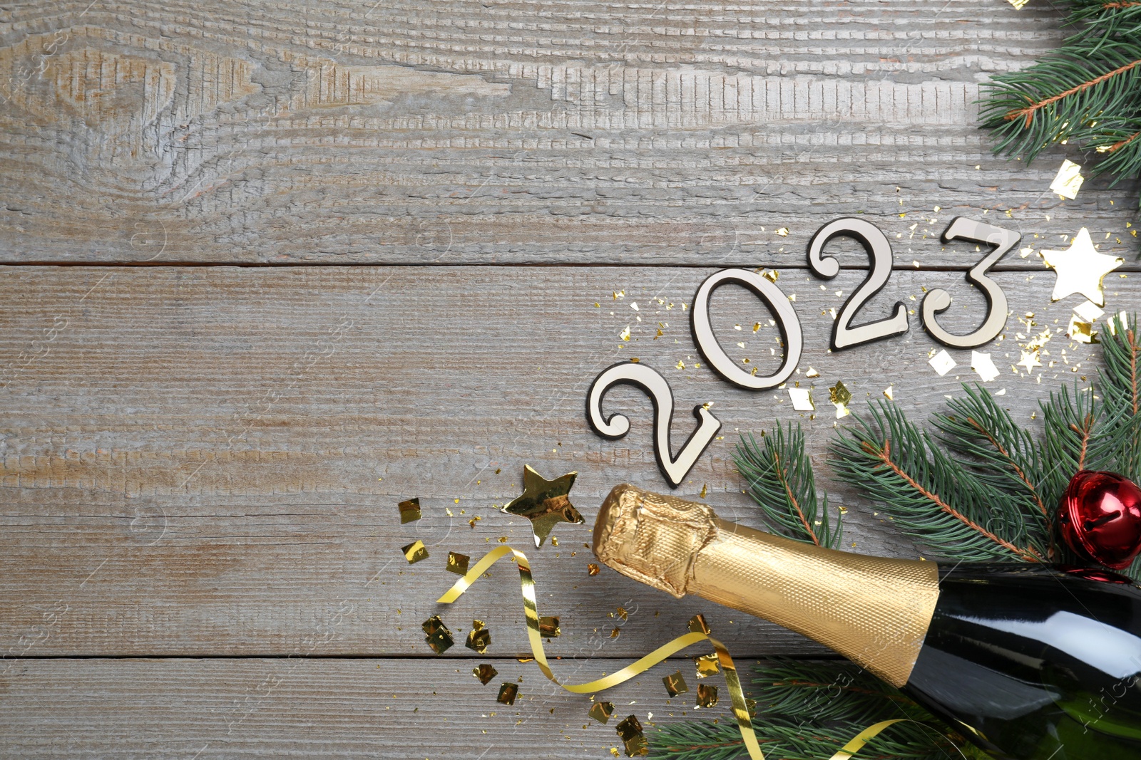 Photo of Happy New Year 2023! Flat lay composition with bottle of sparkling wine on wooden table, space for text