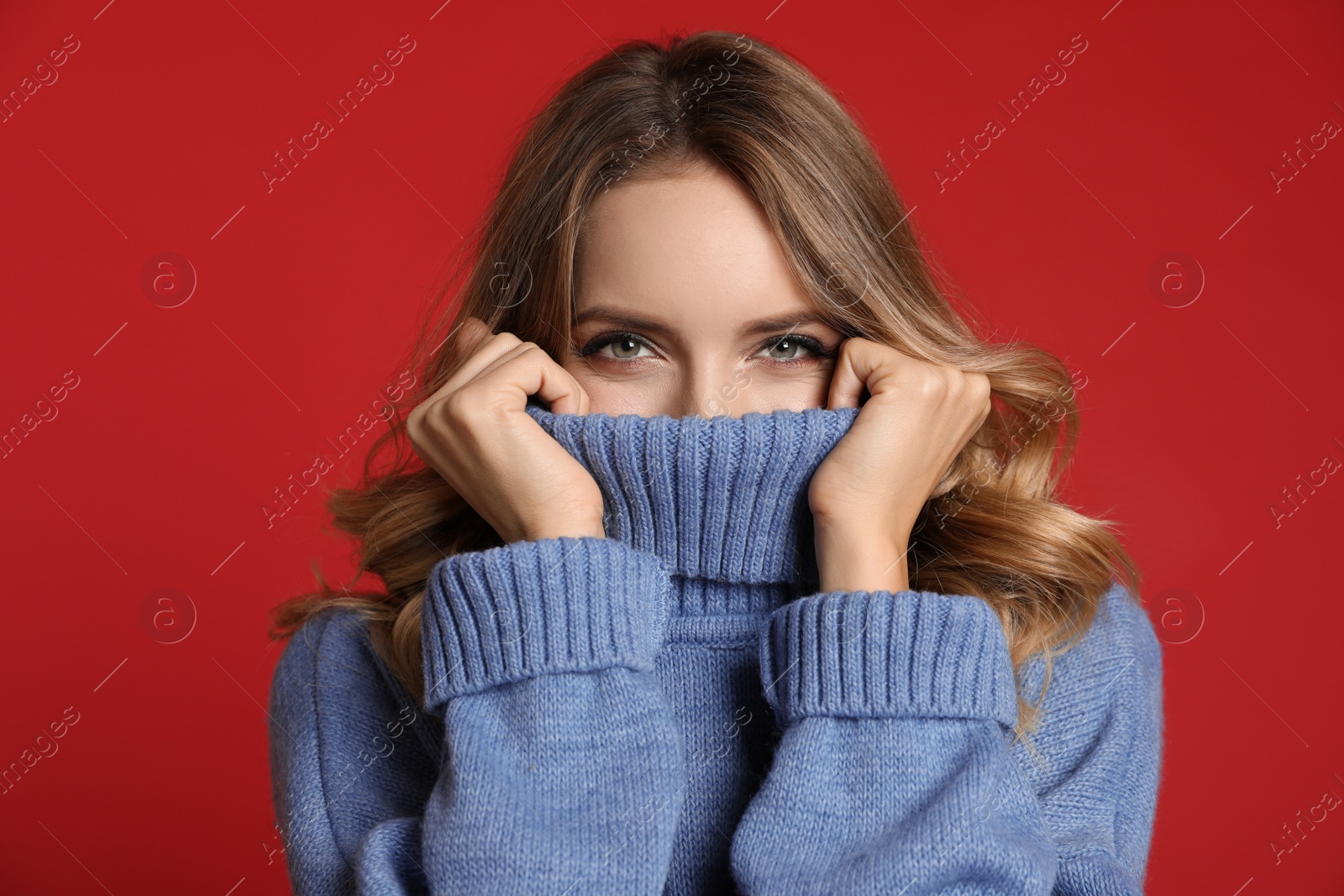 Photo of Happy young woman wearing warm sweater on red background. Christmas celebration
