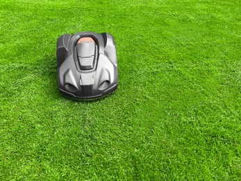 Photo of Modern robot lawn mower on green grass in garden