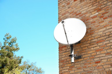 Satellite dish on brick wall of building, space for text