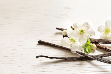 Vanilla sticks and flowers on wooden background
