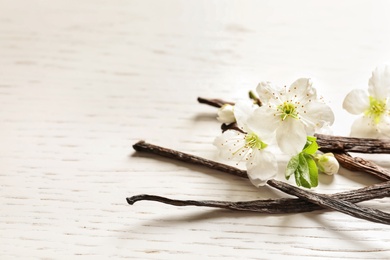 Photo of Vanilla sticks and flowers on wooden background