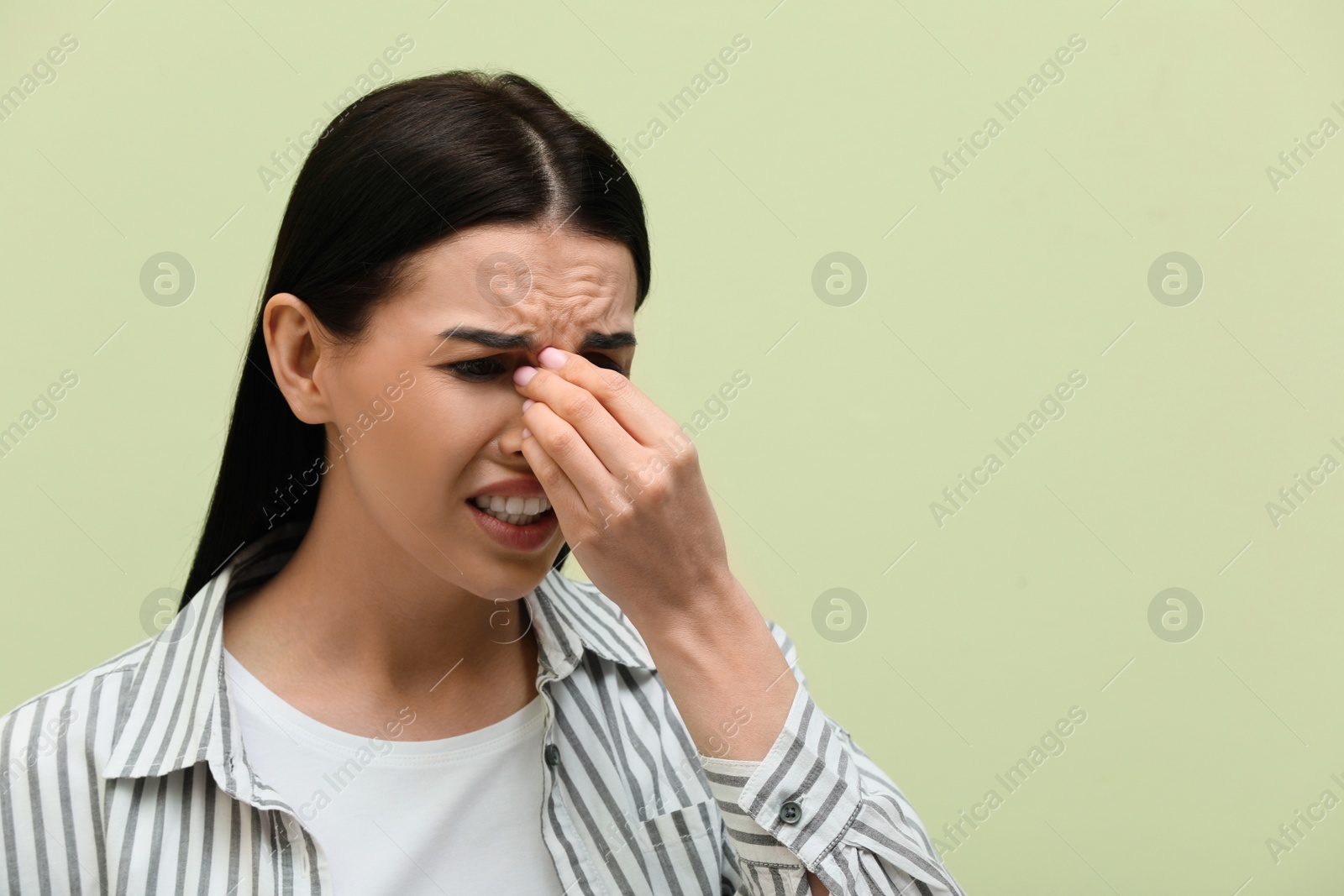 Photo of Woman suffering from migraine on light green background, space for text