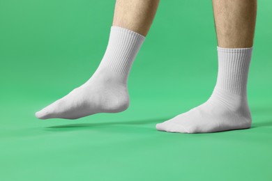 Photo of Man in stylish white socks on green background, closeup