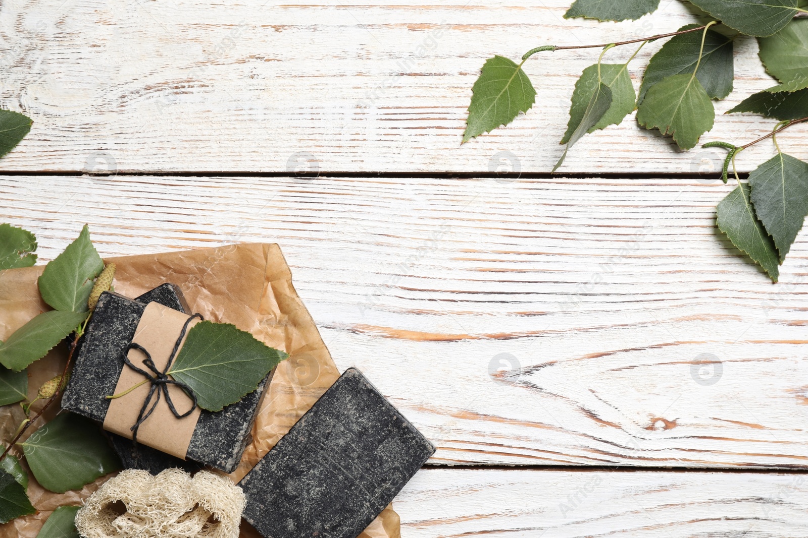 Photo of Natural tar soap on white wooden table, flat lay. Space for text