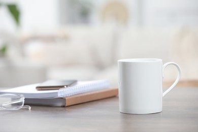 Photo of White ceramic mug and notebooks on wooden table indoors. Space for text