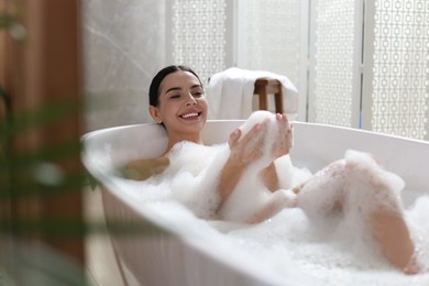 Photo of Beautiful young woman taking bubble bath at home