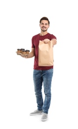 Young courier with paper bag and drinks on white background. Food delivery service