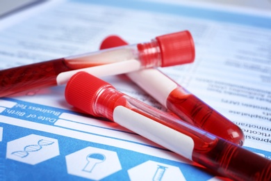 Photo of Sample tubes with blood on laboratory test form, closeup. Research and analysis