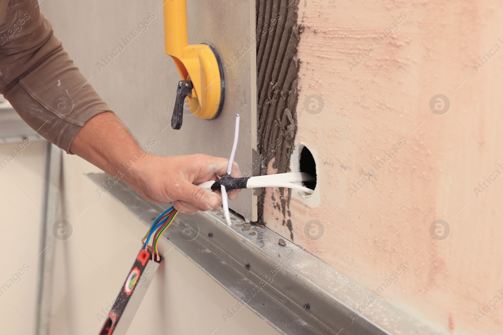 Photo of Worker installing socket in tile indoors, closeup