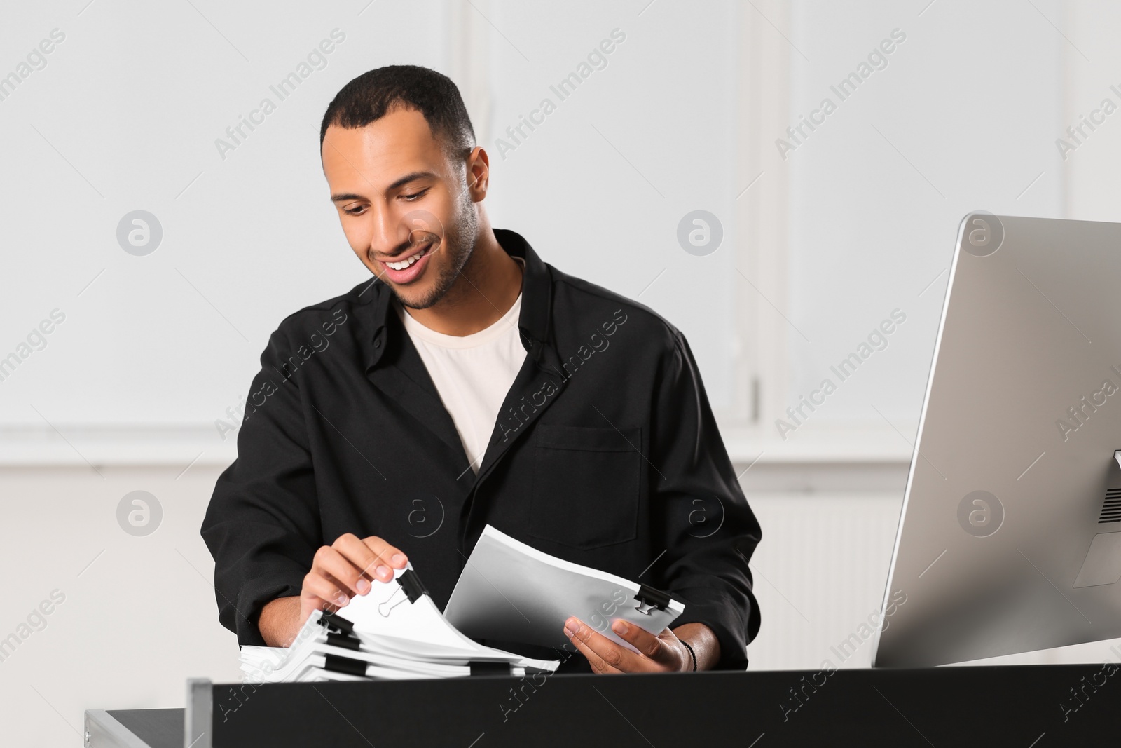 Photo of Happy man working with documents at grey table in office