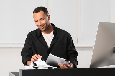 Photo of Happy man working with documents at grey table in office
