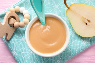 Photo of Flat lay composition with bowl of healthy baby food on pink wooden table