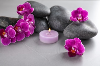 Photo of Spa stones, orchid flowers and candle on grey table