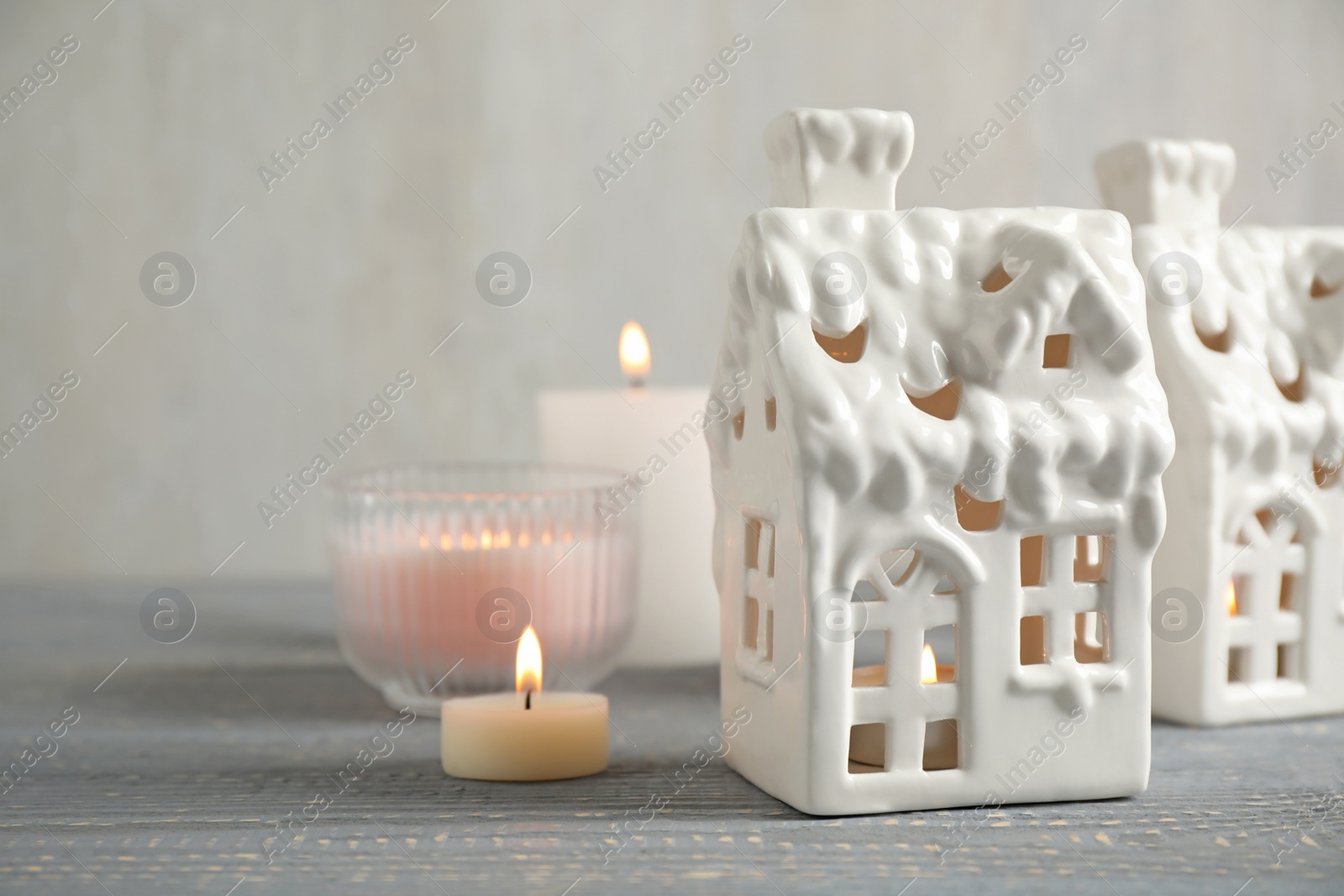 Photo of Composition with house shaped candle holders on grey wooden table, space for text. Christmas decoration